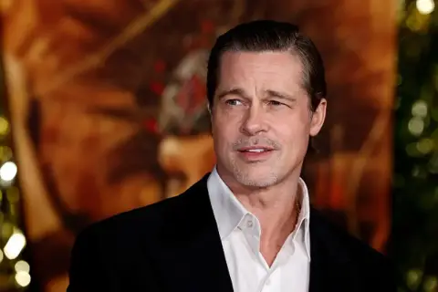 Brad Pitt w czarnym garniturze i białej koszuli, z lekkim zarostem. Wygląda jakby zastanawiał się, kiedy urodził się Brad Pitt.