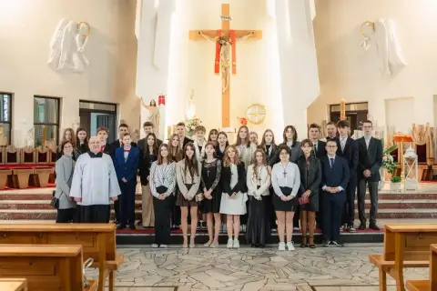 Młodzież w kościele, gotowa do bierzmowania w jakim wieku. Uroczystość z księdzem i rodzinami.