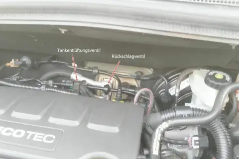 Motorraum eines Opel mit markiertem Tankentlüftungsventil und Rückschlagventil. Der Fehlercode p0171 kann hier relevant sein.