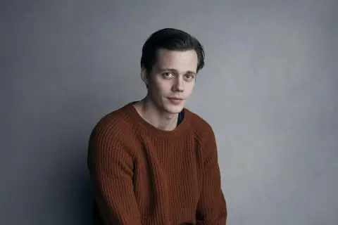 Bill Skarsgård w rudym swetrze, zastanawia się, w jakich filmach grał.