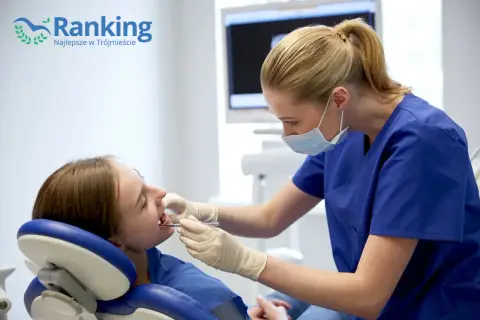 Dentystka w maseczce bada zęby pacjentki w gabinecie stomatologicznym.