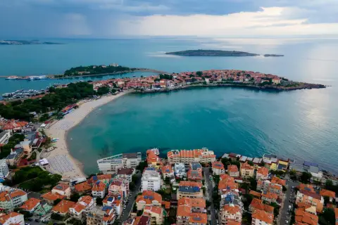 Bułgaria jakie morze? Widok z lotu ptaka na malowniczą zatokę z piaszczystą plażą, urokliwe miasteczko z czerwonymi dachami i turkusowe wody Morza Czarnego.