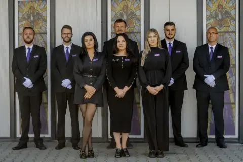 Zespół w czarnych strojach przed witrażem. Jeśli chcesz dowiedzieć się, jak sprawdzić datę pogrzebu, skontaktuj się z nimi.
