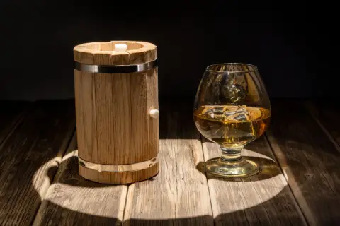 Mała beczka (quarter cask) i kieliszek whisky. Pokazuje skutki starzenia whisky w małych beczkach, przyspieszony proces.