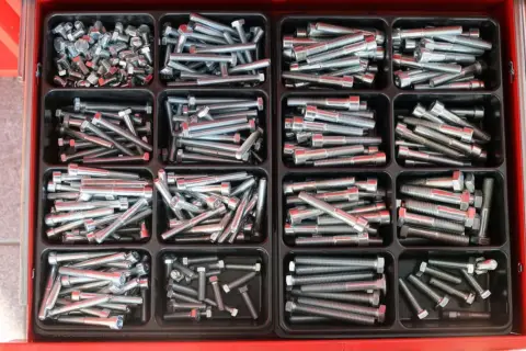 Szuflada z przegródkami pełna śrub i nakrętek, gotowych do użycia. Solidne mocowanie dla każdego projektu.