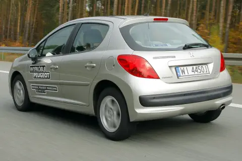 Srebrny Peugeot 207 1.4 benzyna w ruchu drogowym. Na drzwiach naklejka "Wypróbuj Peugeot".