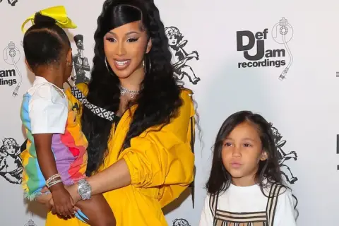 Cardi B z dziećmi na ściance Def Jam. Jedno dziecko w kolorowej stylizacji, drugie obok.