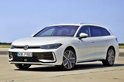 Biały Volkswagen Passat B9 Variant z nowoczesnymi felgami stoi na betonie, z błękitnym niebem w tle.