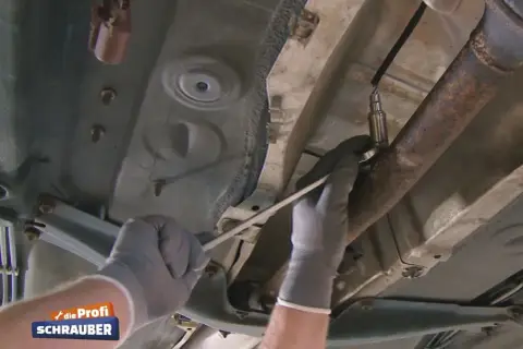 Hände mit Handschuhen wechseln die Lambdasonde an einem Ford Fiesta.