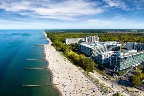 Nowoczesny hotel 5 gwiazdkowy nad morzem z widokiem na plażę pełną wypoczywających.