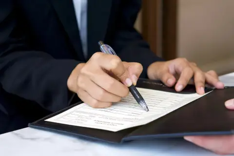 Dłoń w garniturze podpisuje dokument. Czy to umowa, czy może zgoda na warunki, które nawet siła wyższa, jak kodeks pracy, musi uszanować?