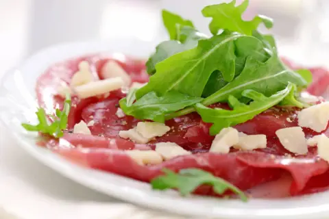 Cienkie plastry wołowiny z rukolą i parmezanem, skropione pysznym sosem do carpaccio.