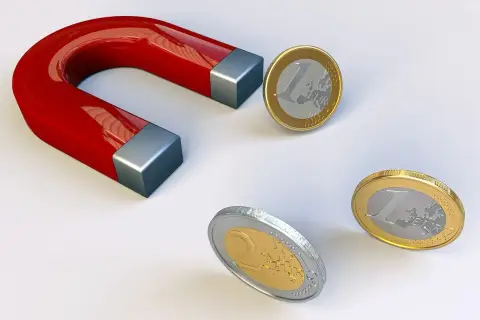 Czerwony magnes podkowowy przyciąga monety euro.