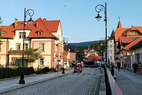 Urokliwa ulica w Świeradowie-Zdroju, z kamienną nawierzchnią i zabytkowymi kamienicami. Idealne miejsce na spacer po uzdrowisku, które przypomina krajobraz z Jeleniej Góry.