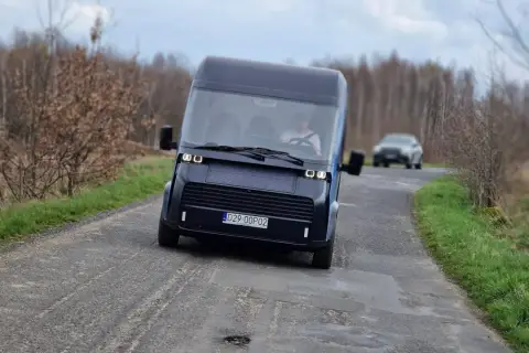 Nowoczesny polski samochód elektryczny przemierza wiejską drogę.