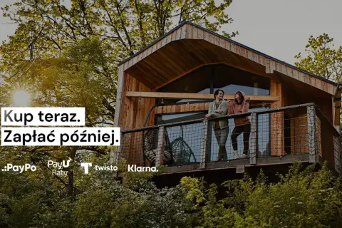 Para, klarna co to? Kup teraz, zapłać później. Dwie osoby na tarasie domku w drzewach.