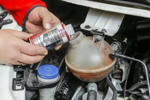 Ręce wlewają Liqui Moly Uszczelniacz chłodnicy do zbiorniczka wyrównawczego.