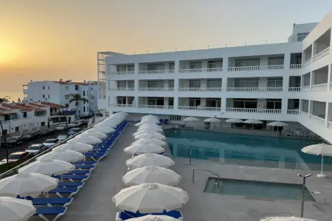 Hotel moderno con piscina y tumbonas, vistas al mar y al atardecer. El azul mar de Lagos de César invita al descanso.