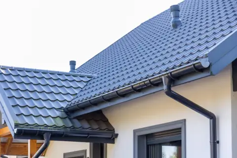 Szary dach z dachówki ceramicznej, idealny do obliczenia dachówka ceramiczna cena za m2. System rynnowy odprowadza wodę.