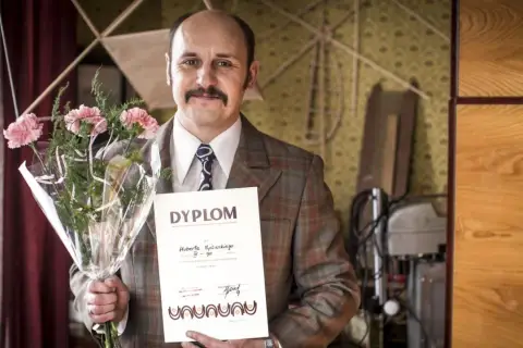 Adam Woronowicz z bukietem i dyplomem, jakby po premierze jednego z jego filmów.