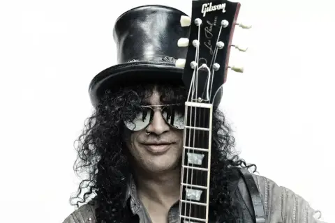 Le guitariste connu Slash, avec son chapeau haut-de-forme et ses lunettes de soleil, tient sa Gibson Les Paul.