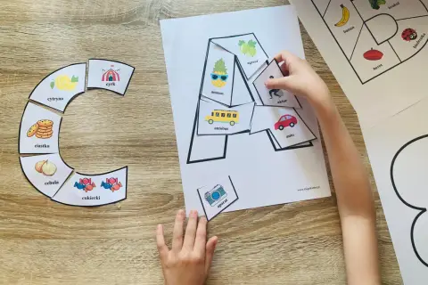Dziecko układa karty pracy z literą "A", dopasowując obrazki: ananas, autobus, aparat.