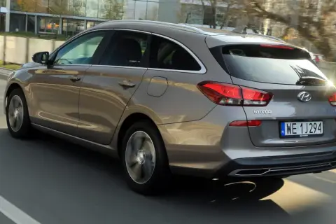 Szary Hyundai i30 1.6 CRDi kombi jedzie po drodze, widać jego tylną część i bok.
