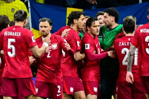 Piłkarze w czerwonych strojach z orzełkiem na piersiach, świętujący sukces. Polska drużyna walczy o mistrzostwa świata.