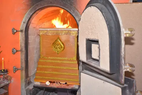 Płomienie otaczają drewnianą trumnę w piecu kremacyjnym, pokazując, co się dzieje z ciałem podczas kremacji.