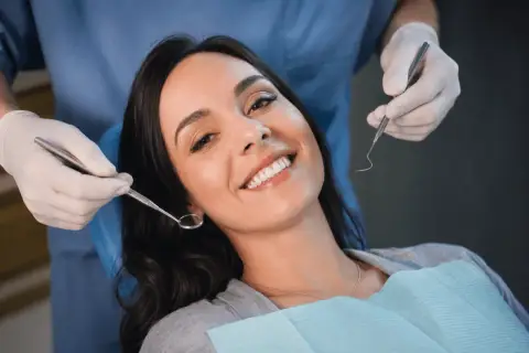 Uśmiechnięta pacjentka u dentysty, która mimo narzędzi nie wykazuje odruch wymiotny.