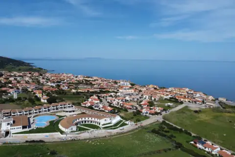 Widok z lotu ptaka na kurort GH Santina Resort z basenem i budynkami, nad morzem na Sardynii.