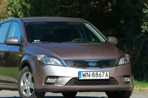 Brązowe Kia Ceed z przodu, na tle zieleni.