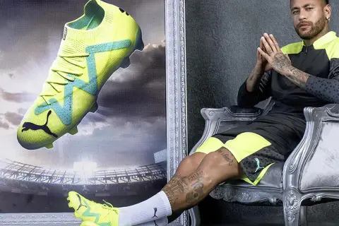Neymar w neonowych butach piłkarskich Puma, idealnych na sztuczną trawę, siedzi na tronie.