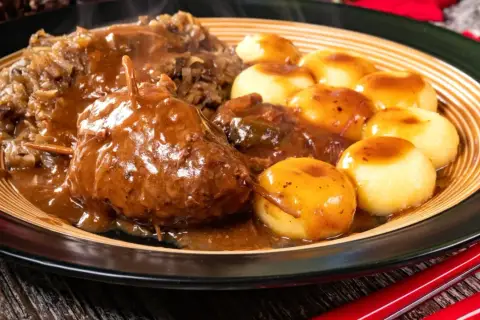 Pyszne mięso do klusek śląskich w sosie, podane z kapustą i ziemniaczanymi kluseczkami.