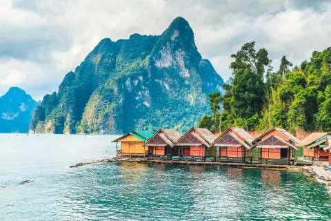 Bungalows auf dem Wasser vor einer Bergkulisse im thailand nationalpark.