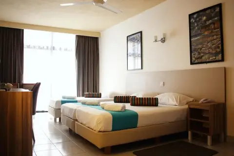 Pokój w hotelu Canifor Malta z dwoma łóżkami, zasłonami i widokiem na zewnątrz.