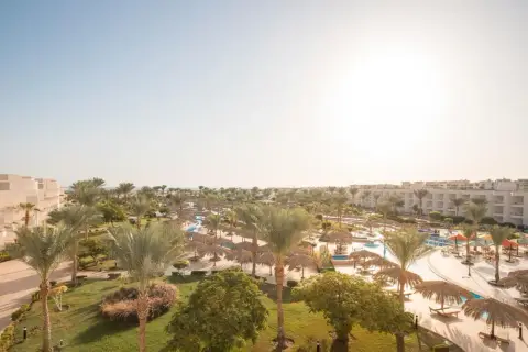 Słoneczny dzień w kurorcie Long Beach Resort Hurghada. Palmy, baseny i leżaki pod strzechą zapraszają do relaksu.