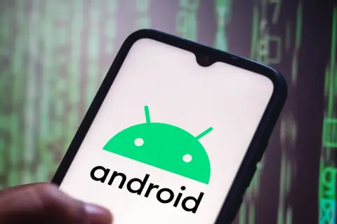 Dłoń trzyma smartfon z logo Android 10. Tło to zielony, rozmyty kod.