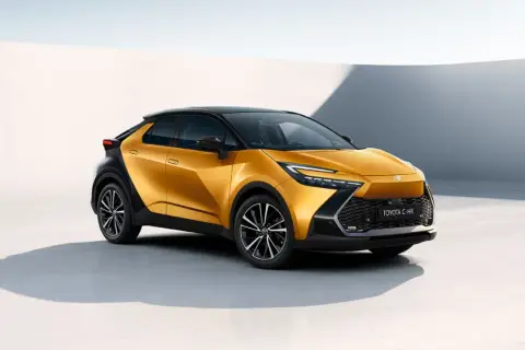 Nowa Toyota C-HR w kolorze złoto-czarnym, stylowa toyota hybryda, prezentuje się dynamicznie na tle minimalistycznej architektury.