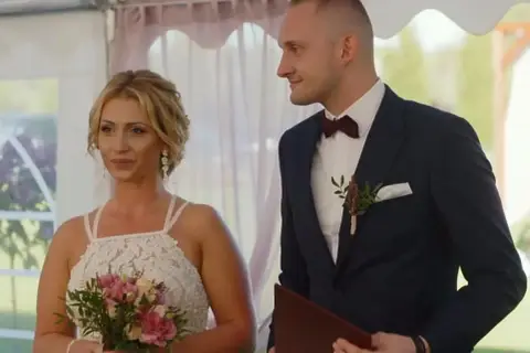 Iza i Kamil, ślub od pierwszego wejrzenia. Panna młoda z bukietem, pan młody w garniturze, patrzą na siebie z uśmiechem.