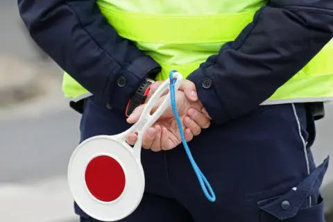 Policjant w kamizelce odblaskowej trzyma znak stop. Zastanawiasz się, ile km można jechać na autostradzie?