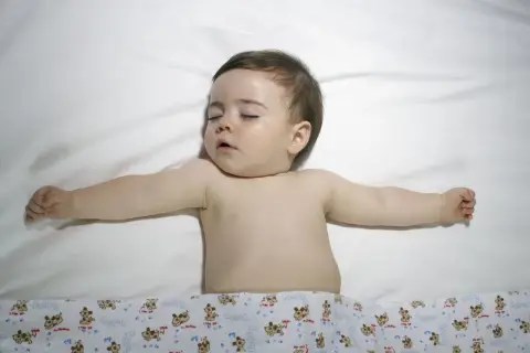 Śpiące dziecko z rozłożonymi rączkami. Choć obrazek nie sugeruje zespołu Turnera, warto pamiętać o jego istnieniu.