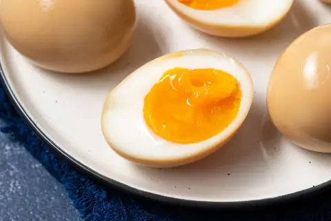 A plate of perfectly cooked onsen eggs, some whole and some halved to reveal their creamy, golden yolks.