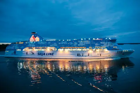 Prom Silja Line Galaxy płynie po wodzie, odbijając światła. Podróż z Rygi do Helsinek nocą.