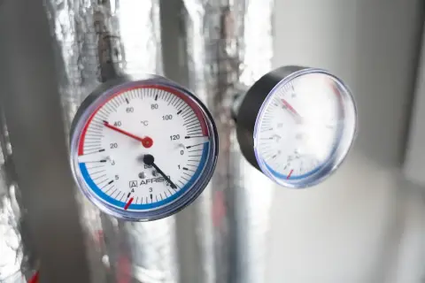 Dwa manometry na izolowanych rurach pokazują temperaturę i jakie ciśnienie wody w domu jest optymalne.