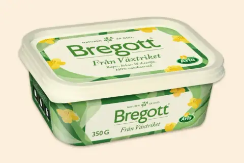 En förpackning Bregott Från Växtriket med raps-, kokos- och sheaolja. Den är 100% växtbaserad och har ett grönt mönster med gula blommor.