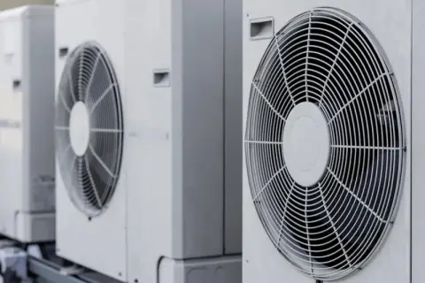 Trzy jednostki zewnętrzne klimatyzatorów, które mogą posłużyć do konwersji na pompę ciepła, stoją obok siebie na dachu.