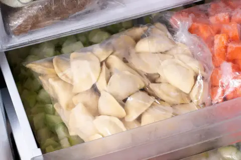 Jak mrozic domowe pierogi? W zamrażarce leżą woreczki z pierogami, mrożonymi warzywami i innymi produktami.
