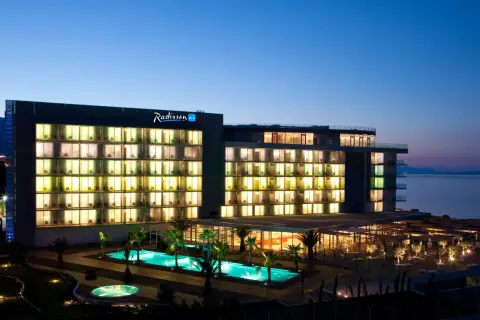 Hotel Radisson Blu Split nocą, z podświetlonymi oknami, basenami i palmami.