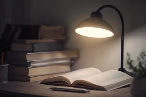 Stół z książkami i lampką. Idealne oświetlenie, by sprawdzić, ile lumenów do czytania jest potrzebne.